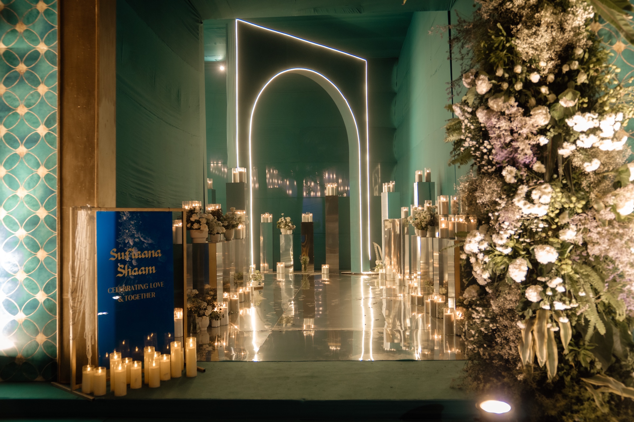 Sufiyana Shaam entrance with a glowing arch, mirrored floor, candles and white flowers