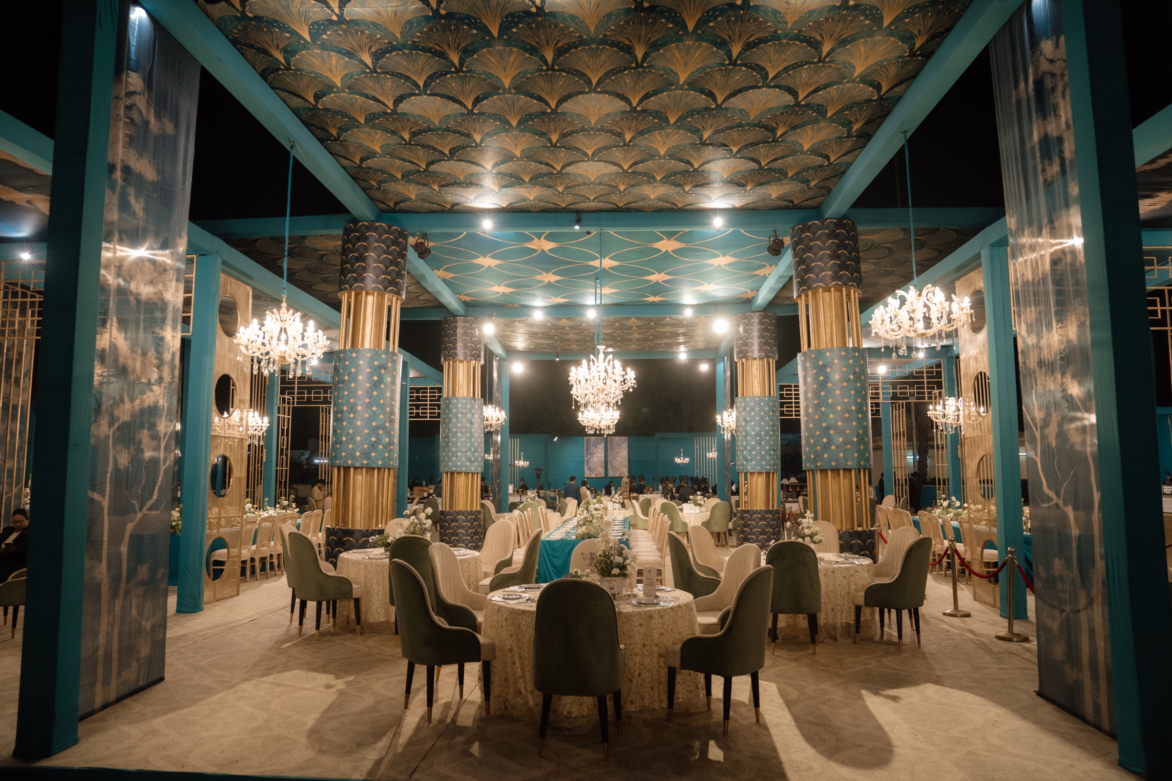 Kabra golden anniversary venue in teal and gold, lit by crystal chandeliers